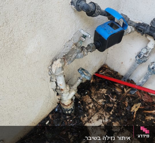 צינורות מים עם ברז כחול על קיר חיצוני
